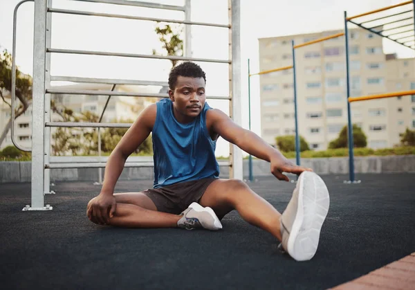 Afro-americano joven fitness hombre estirando su pierna y calentando para el entrenamiento en el gimnasio al aire libre parque —  Fotos de Stock