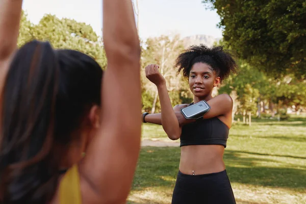 Diverse vrouwelijke vrienden staan 's ochtends samen te trainen in het park - fitnessvrienden warmen hun spieren samen op tijdens het chatten — Stockfoto