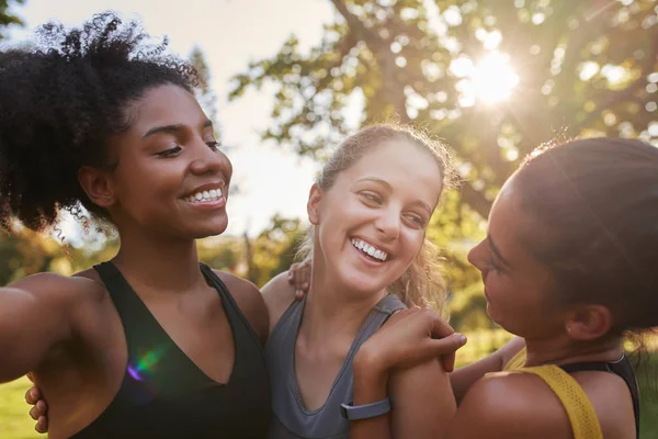 Grupp av olika kvinnliga vänner ler och ha kul tillsammans på solig dag i parken - glada fitness vänner skrattar med varandra på en solig dag — Stockfoto