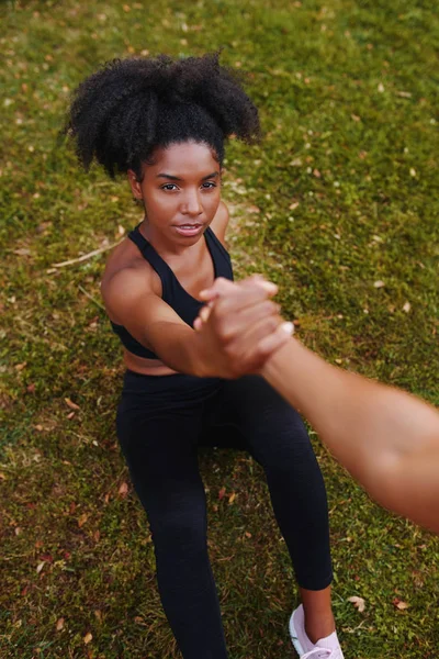 Una vista por encima de la joven deportista sosteniendo la mano de su amiga mientras la ayuda a despegar del suelo — Foto de Stock