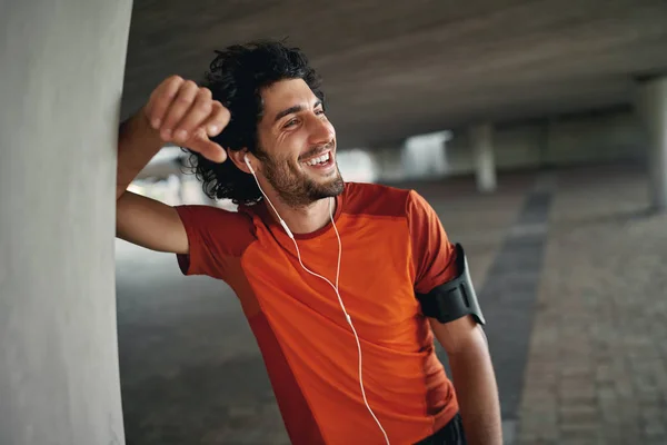Portrait of healthy happy young caucasian man standing outdoor and looking away enjoy the music on earphone after run - happy runner — Stok Foto