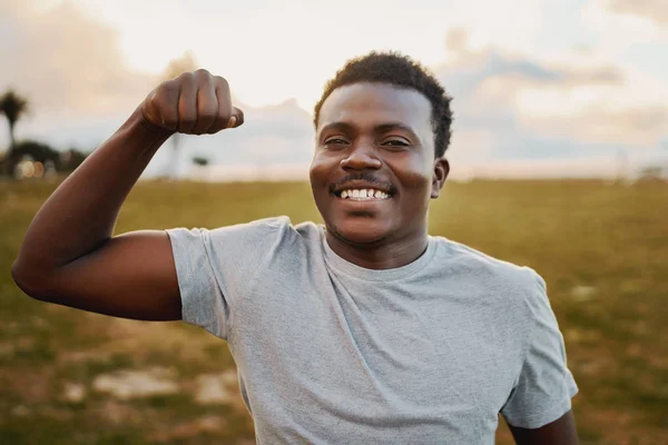 Retrato de um jovem atleta alegre sorrindo e dando soco na frente da câmera no parque — Fotografia de Stock