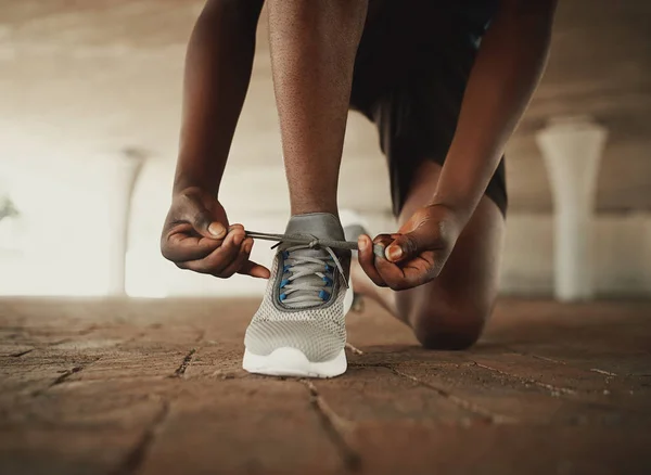 Immagine ritagliata delle mani che legano i lacci delle scarpe da ginnastica sulla superficie del pavimento — Foto Stock