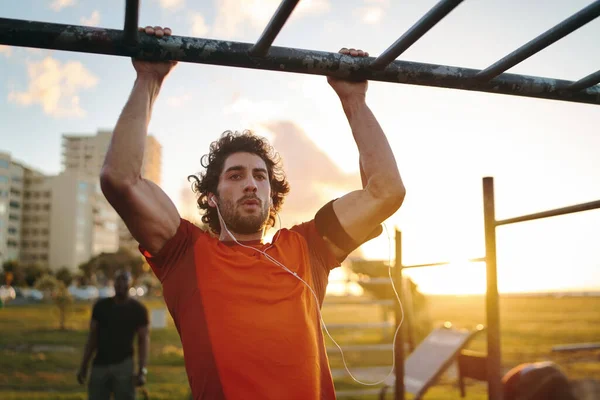 Retrato de um jovem desportista crossfit exercitando-se no bar, fazendo pull-ups para braços e músculos das costas no parque de ginásio ao ar livre — Fotografia de Stock