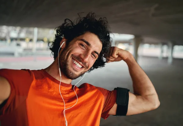 Deportista guapo sonriente confiado tomando una selfie y flexionando los músculos mientras mira a la cámara — Foto de Stock