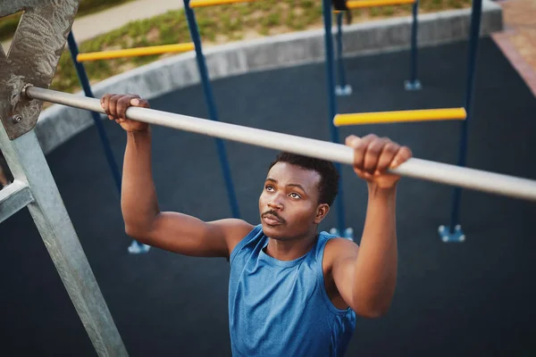 Fuerte en forma joven afroamericano hombre haciendo pull-ups en un bar en un parque gimnasio al aire libre —  Fotos de Stock