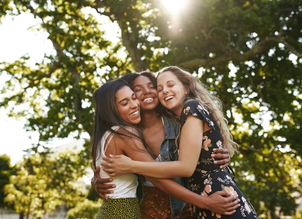 Portrait of happy three multiethnic multiracial female friends closely hugging and showing care and love for each other in park — Stok fotoğraf