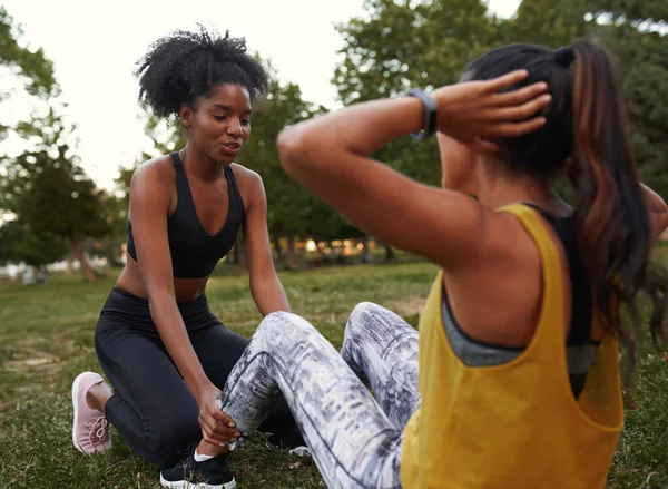Afro-Amerikaanse vriend helpen om haar vriend te ondersteunen doen sit-ups in het park - vrouwelijke vrienden doen oefening buiten in het park — Stockfoto