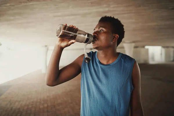 Afro-americano jovem bebendo água de garrafa depois de correr ao ar livre — Fotografia de Stock