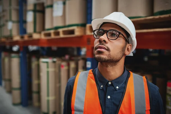 Magazijn mannelijke supervisor in uniform en helm denken staan in de fabriek weg te kijken — Stockfoto