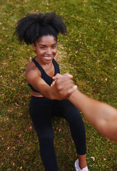 An above view of smiling african american sporty young woman getting help from her friends while doing workouts in park — Stockfoto