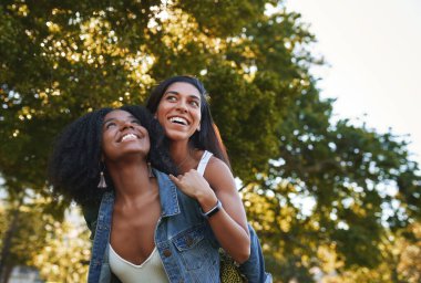 Güneşli bir günde parktaki en iyi kız arkadaşını sırtında taşıyan gülümseyen Afro-Amerikan bir kadının portresi. Kampüste gülüp eğlenen bir grup üniversite öğrencisi.