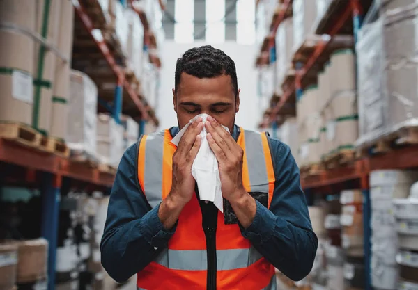 Giovane magazziniere africano malato che soffia il naso mentre lavora indossando un giubbotto di sicurezza — Foto Stock