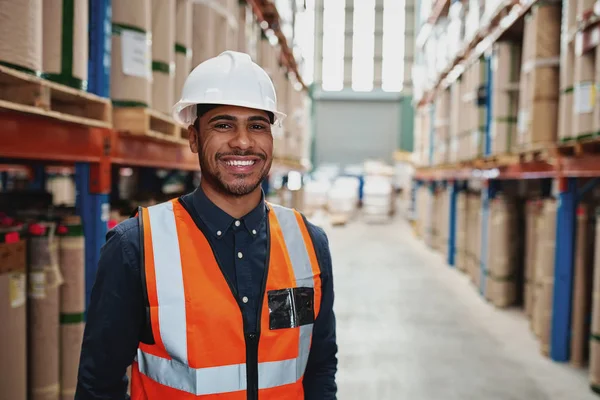 Felice supervisore maschio in magazzino in piedi in uniforme con hardhat bianco sorridente guardando la fotocamera - copiare lo spazio a destra — Foto Stock