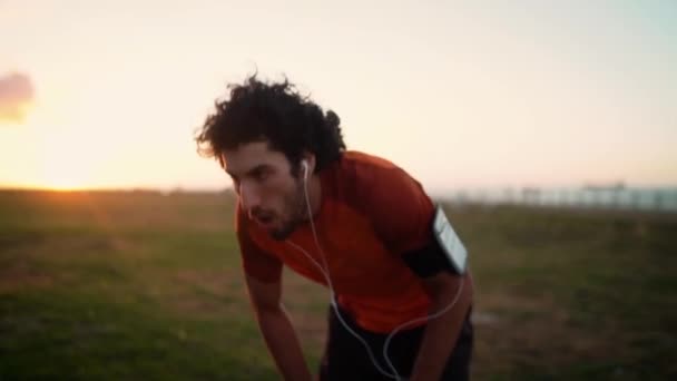 Exhausted athlete young man resting hands on knees taking a rest and catches a breath after running in the park — Stockvideo