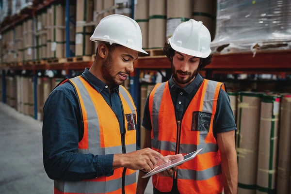 Giovani lavoratori concentrati in magazzino discutono di lavoro su tablet digitale — Foto Stock