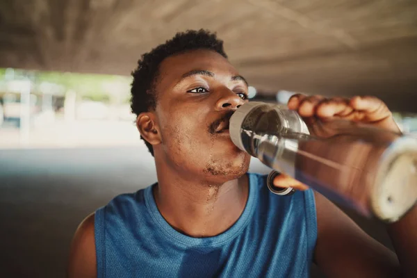 Retrato de um jovem afro-americano fitness bebendo água de garrafa ao ar livre — Fotografia de Stock