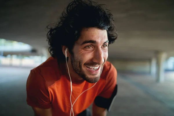 Retrato de cerca de un hombre feliz joven en forma agotada con auriculares en sus oídos tomando un descanso después de trotar en el parque - resoluciones de año nuevo — Foto de Stock