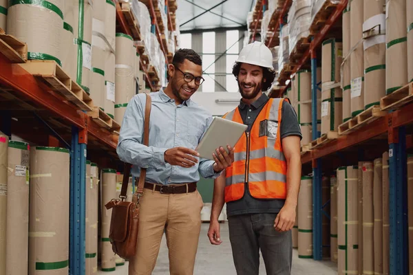 Bank manager showing loan options to warehouse manager using digital tablet in modern factory