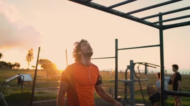 Jonge atleet man doen pull-ups oefeningen op horizontale balk op sportveld — Stockvideo