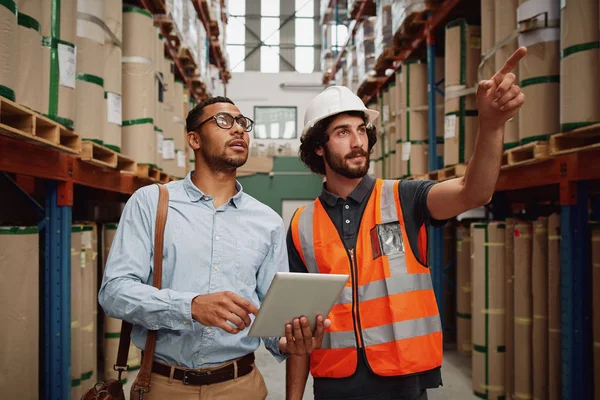 Magazzino manager indossando casco che punta verso scaffale in magazzino — Foto Stock