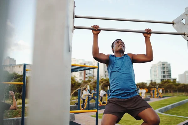 Vista frontal de un fuerte atleta afroamericano haciendo pull-up en barra horizontal en el parque público de gimnasia —  Fotos de Stock