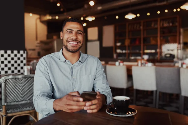 Jovem africano feliz sentado no café usando telefone celular olhando para a câmera — Fotografia de Stock