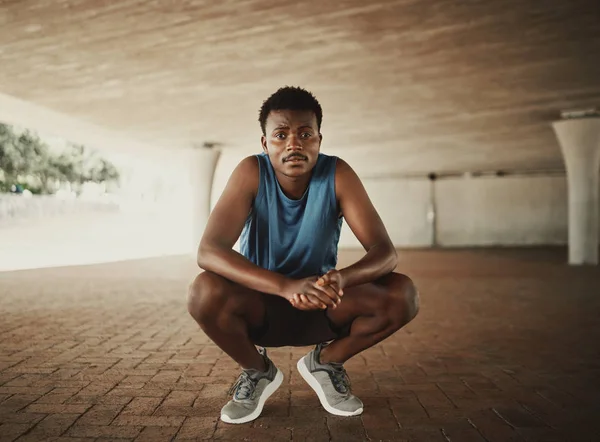 Retrato de um corredor de fitness em sportswear agachado no pavimento e olha para a câmera — Fotografia de Stock