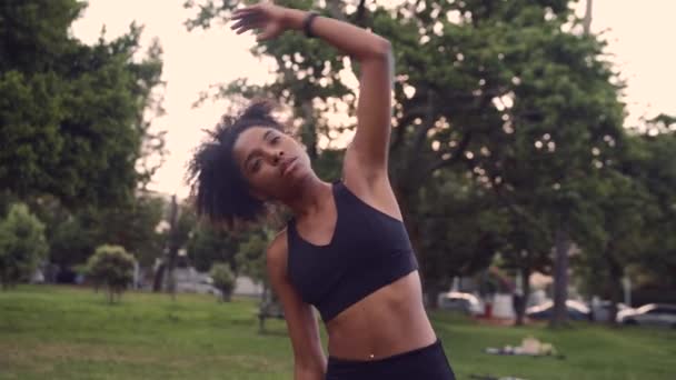 Портрет здоровой девушки, вытянувшей руки, разогретой в парке — стоковое видео