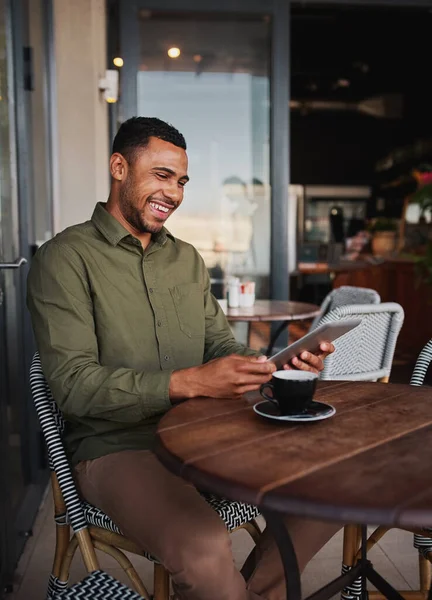 Щасливий молодий афроамериканський чоловік використовує цифровий планшет в офісних кафетеріях під час пиття кави — стокове фото