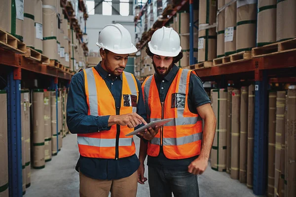 Giovani lavoratori concentrati in magazzino discutono di lavoro su tablet digitale — Foto Stock