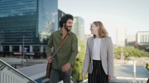 Szczęśliwy młody biznesmen i bizneswoman chodzący na górę w mieście uśmiechając się i rozmawiając — Wideo stockowe