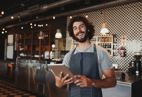 Bello giovane proprietario della caffetteria caucasica che indossa grembiule ridere utilizzando tablet digitale — Foto Stock