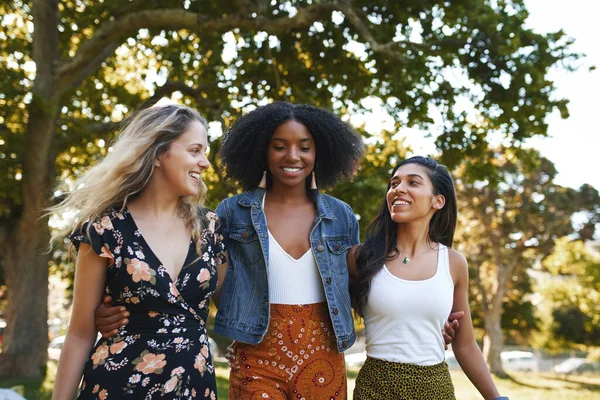 Groupe d'amies souriantes et multiraciales heureuses marchant ensemble dans le parc par une journée ensoleillée — Photo