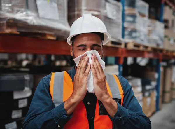 Young african manager coughing and feeling sick while covering mouth with handkerchief in warehouse — Stockfoto