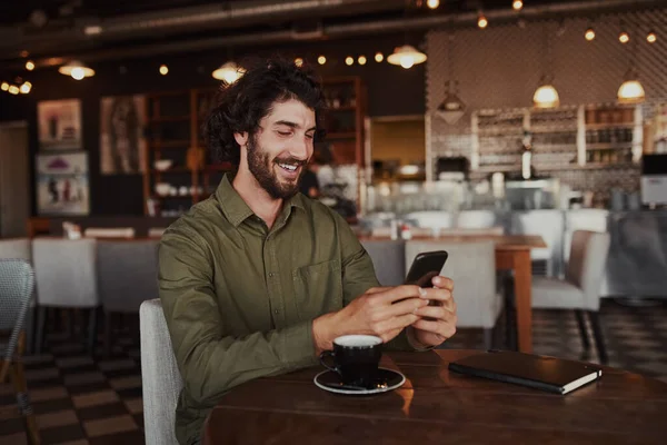 Белый мужчина с чашкой кофе и чтением текстовых сообщений на смартфоне — стоковое фото