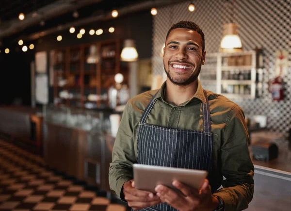 Hombre afroamericano joven con delantal de pie usando tableta digital en la cafetería — Foto de Stock