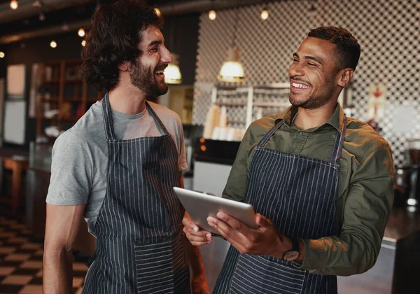 Allegro colleghi di sesso maschile utilizzando tablet digitale sul bancone del caffè e ridendo — Foto Stock