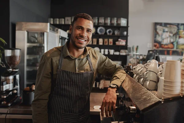 Portrait of young afro-american male business owner behind the counter of a coffee shop smiling looking at camera — Stockfoto