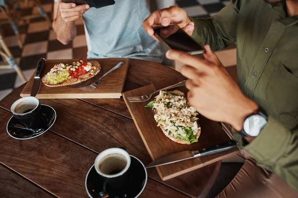 Primer plano de la mano del hombre haciendo clic en la foto de la bruschetta italiana con café en la cafetería mientras disfruta del almuerzo —  Fotos de Stock