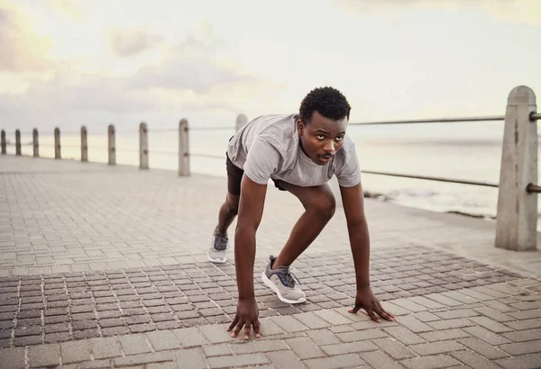 Joven atleta masculino listo para correr en la sesión de entrenamiento en el paseo marítimo por la mañana —  Fotos de Stock
