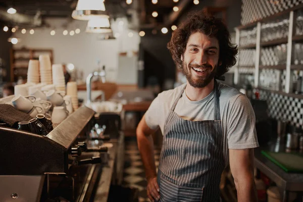 Retrato de bonito jovem dono de café masculino em pé atrás do balcão — Fotografia de Stock