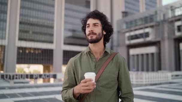 Retrato de sorridente jovem empresário em pé ao ar livre na frente de um moderno pátio de escritório segurando takeaway xícara de café — Vídeo de Stock