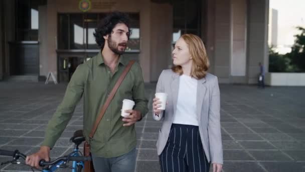 Άντρας περπατά με το ποδήλατό του και γυναίκα συνάδελφος φίλος κρατώντας φλιτζάνι καφέ μπροστά από το εταιρικό κτίριο μιλάμε και χαμογελά — Αρχείο Βίντεο