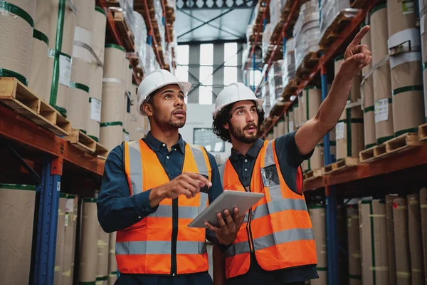 Operaio teso in fabbrica che mostra scaffali al suo manager con tablet digitale con hardhat e gilet di sicurezza — Foto Stock