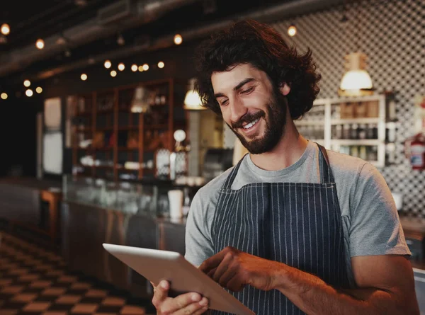 Joyeux jeune propriétaire de café caucasien portant tablier à l'aide d'une tablette numérique — Photo