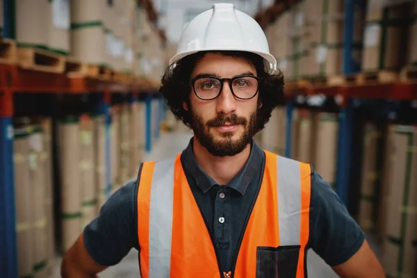 Ritratto di giovane operaio caucasico fiducioso in berretto bianco e tuta protettiva con occhiali in piedi in negozio industriale — Foto Stock