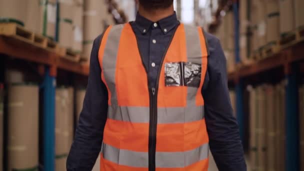 Портрет улыбающегося уверенного работника склада, стоящего со скрещенными руками на большом складе и смотрящего в камеру — стоковое видео