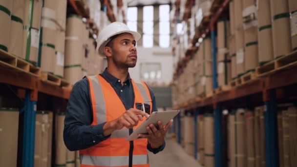 Ritratto in vita del moderno magazziniere afroamericano con tablet digitale che alza lo sguardo verso alti scaffali nel magazzino — Video Stock