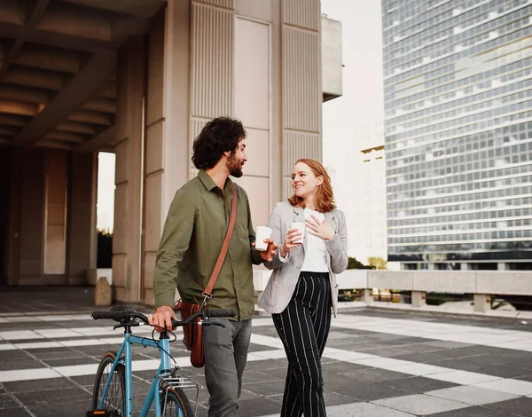 Hombre de negocios con bicicleta y bolsa de honda caminando con la mujer sosteniendo taza de café desechable — Foto de Stock